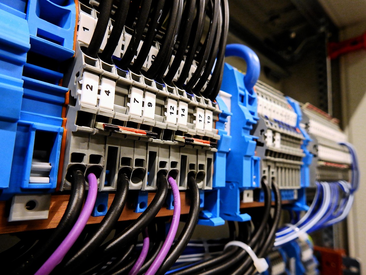 Reihenklemmen, Sammelschiene und farbige Adern im Inneren eines elektrischen Verteilerschranks