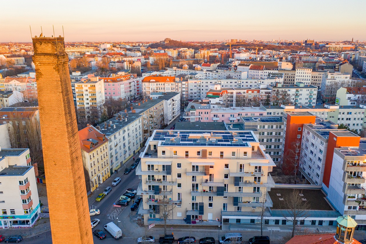 Luftbild einer Stadt mit Wohnblöcken, auf mehreren Flachdächern liegen Photovoltaikmodule.